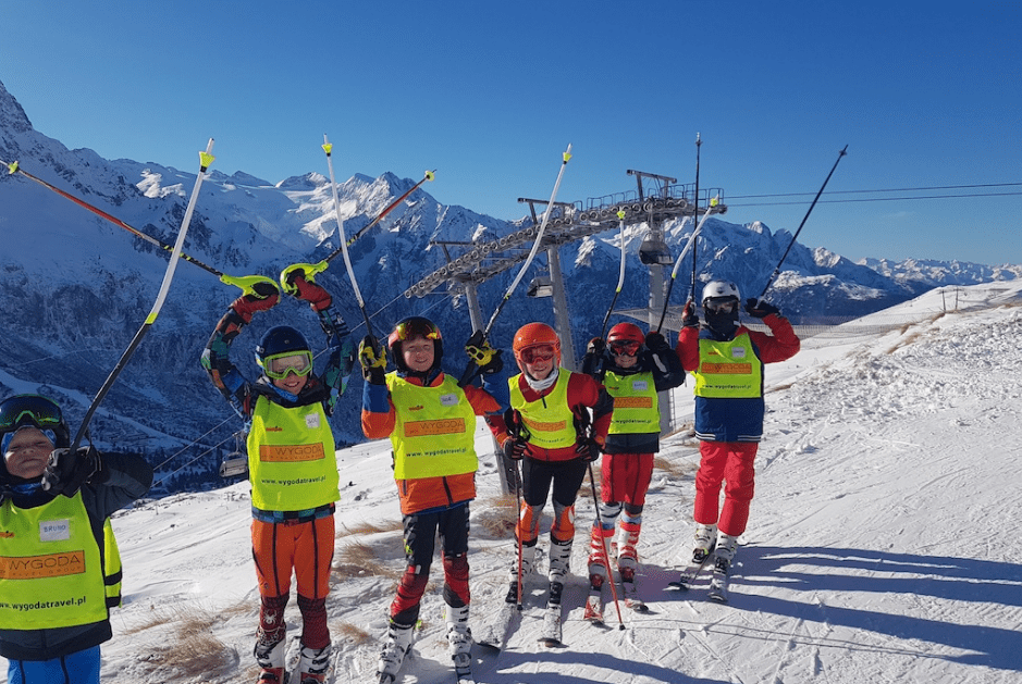 Uśmiechnięci mali narciarze w pobliżu wyciągu narciarskiego.